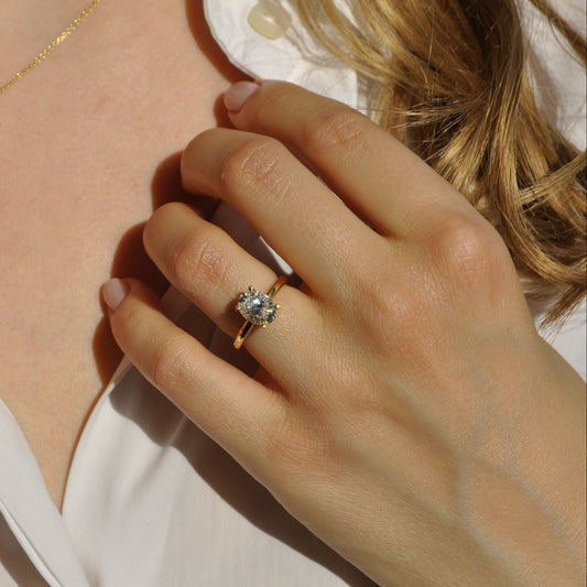 Close-up of a person wearing two diamond rings on their fingers, with a necklace in the background.