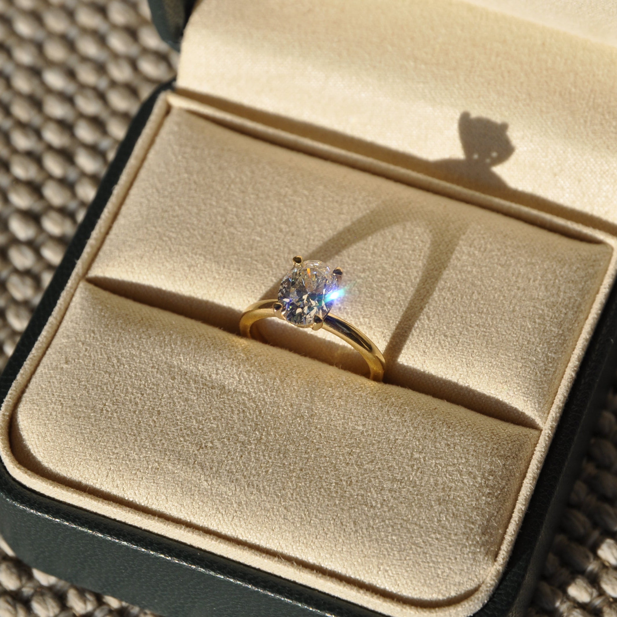 Gold ring with a diamond in a jewelry box on a textured surface